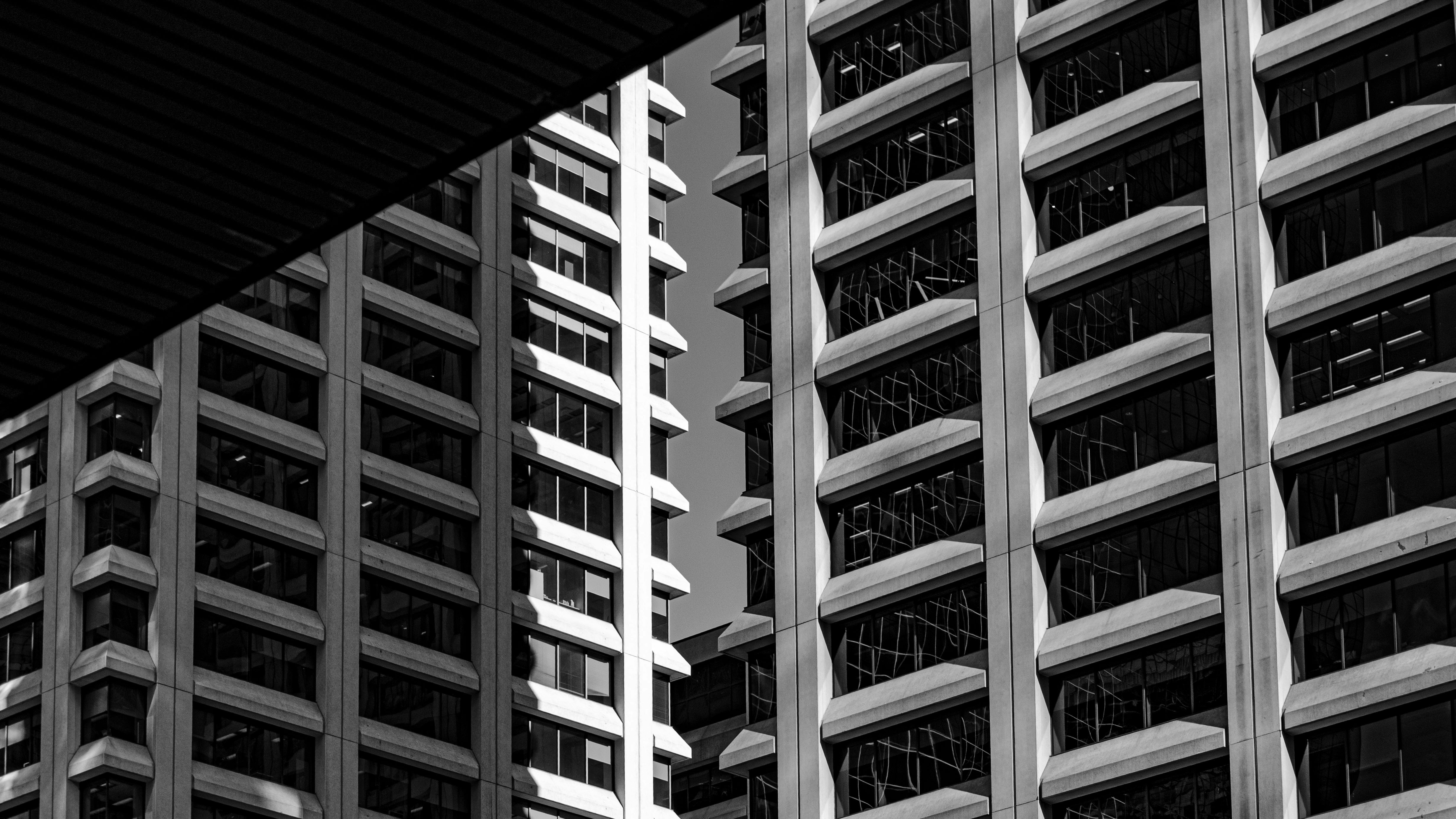 Repeating rows of windows on modern high-rise buildings, photographed in black and white.