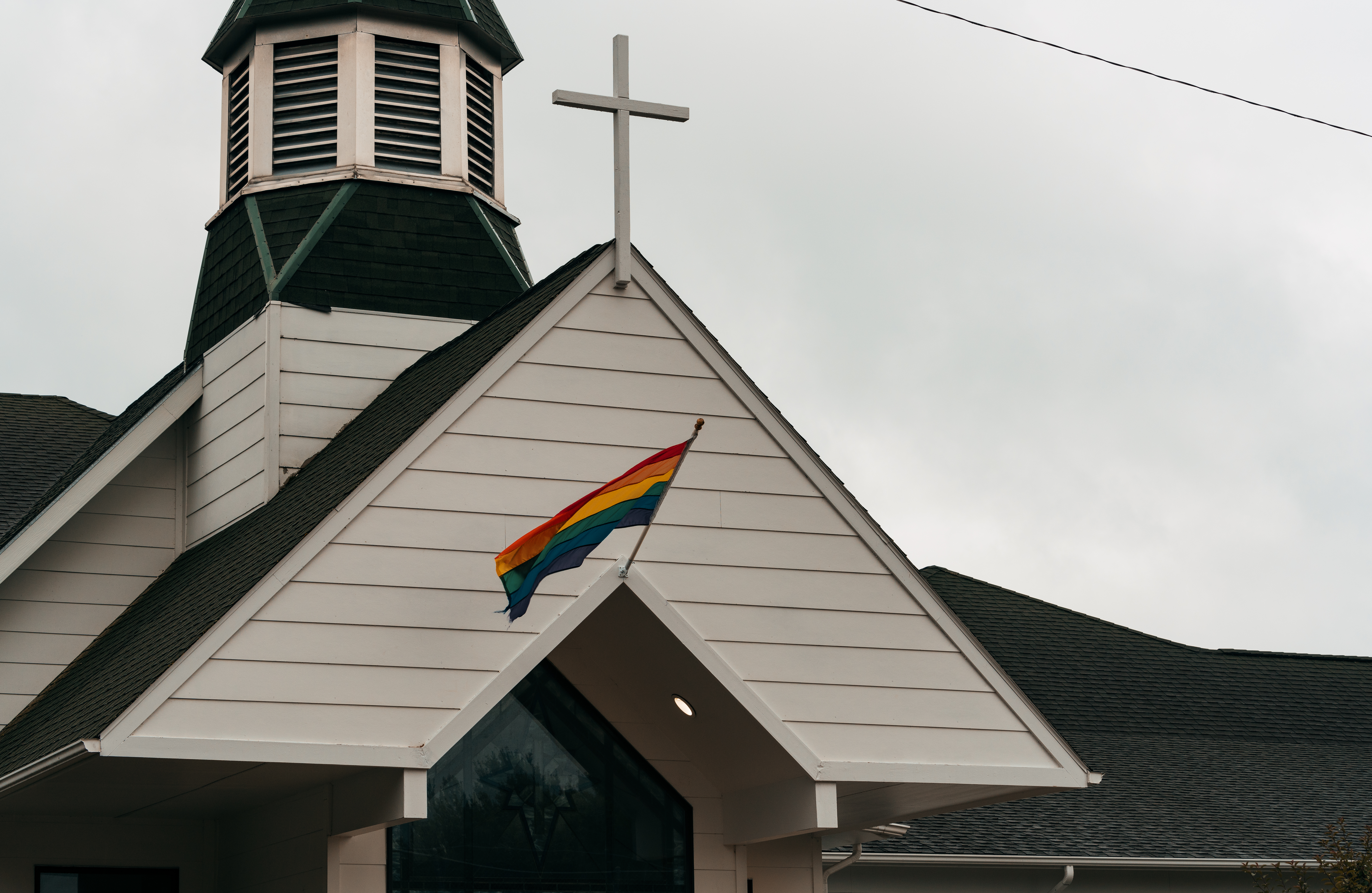 A rainbow Pride flag flies beneath a white cross at Union Congregational Church in Hackensack, Minnesota.